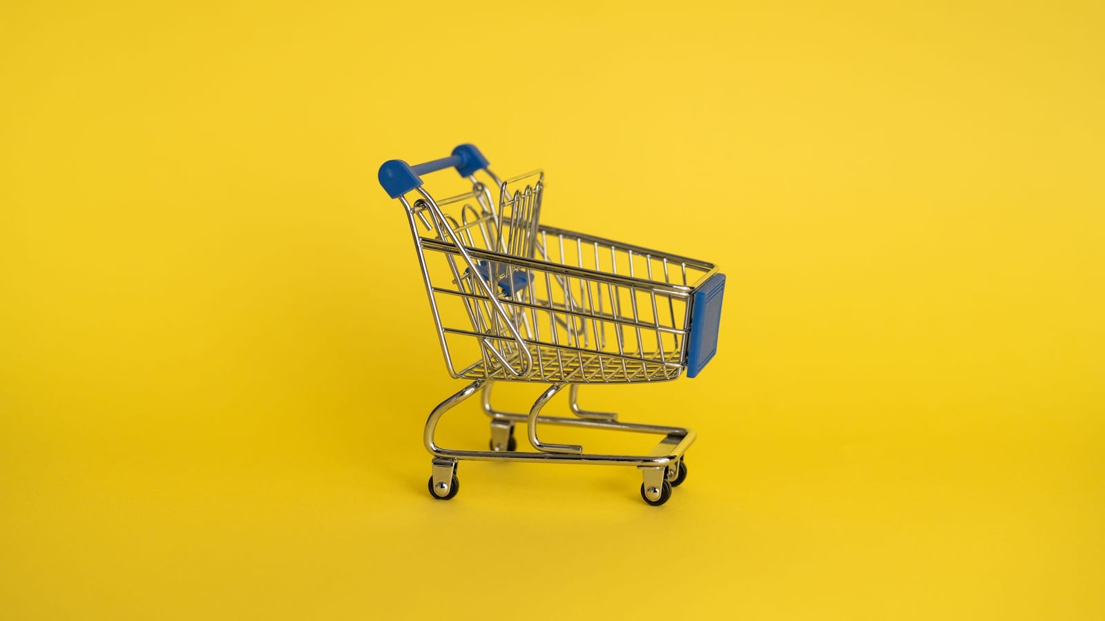 A small empty shopping cart on a yellow background