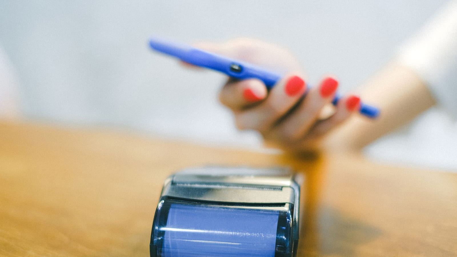A hand holding a phone to a card terminal to pay