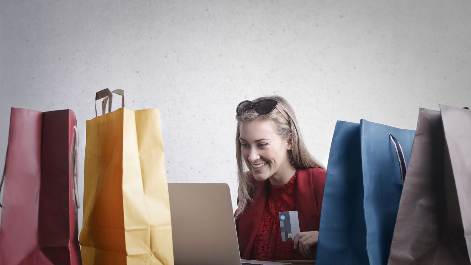 A happy woman shopping on her laptop with shopping bags around her