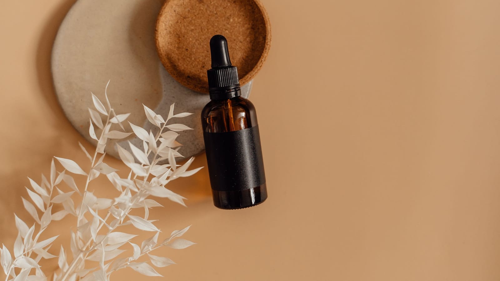 A skincare bottle with a dropper in a styled product flat lay