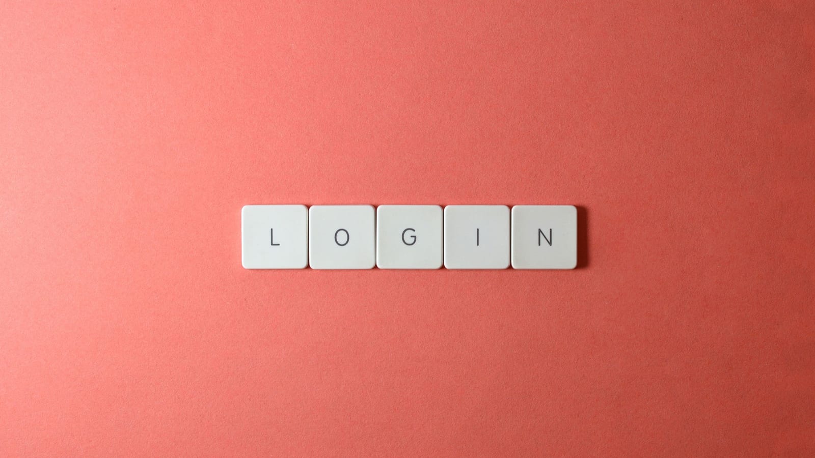 Letter tiles spelling login on a coral background