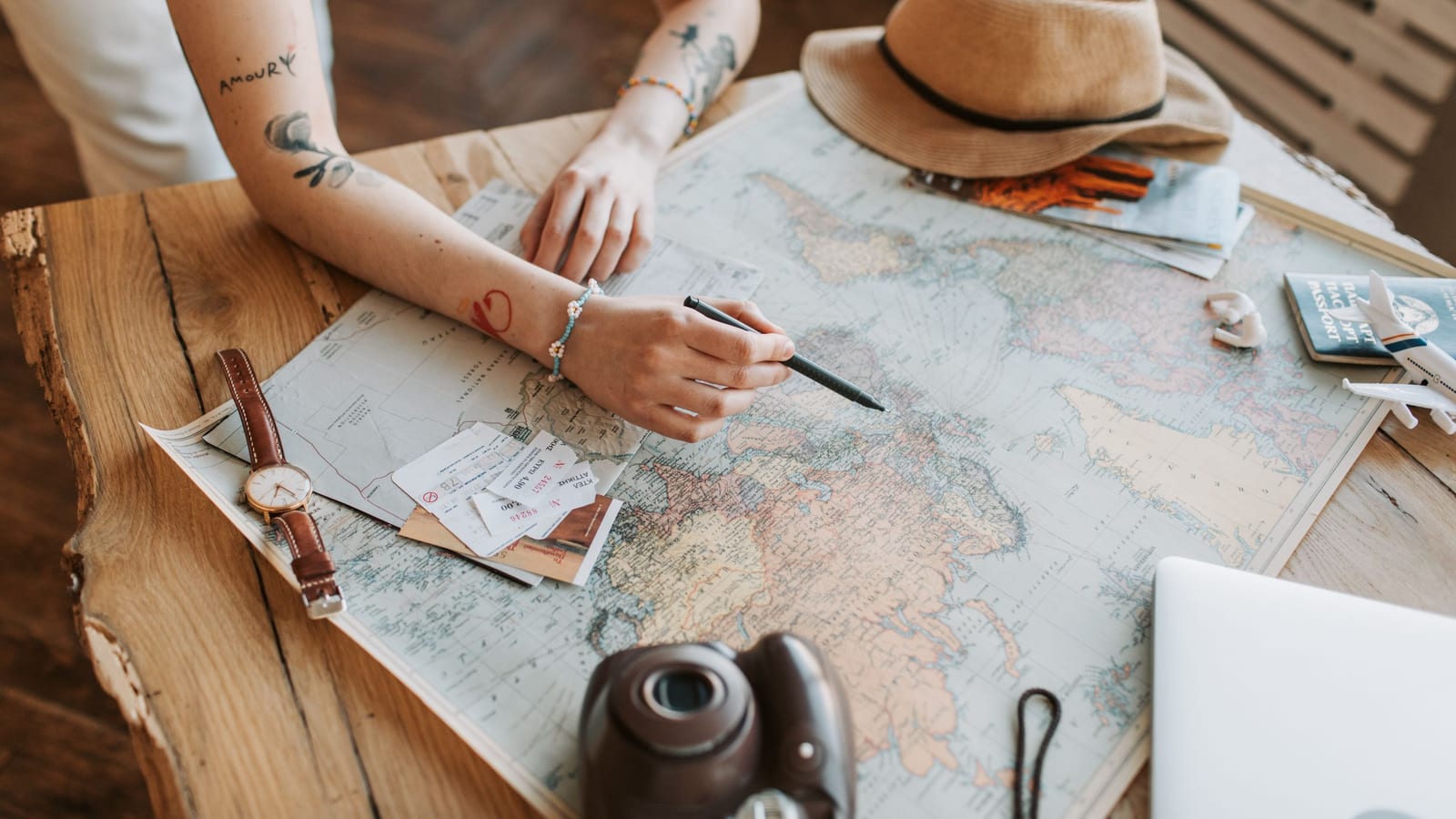 A woman planning on a world map with passports on a wooden table