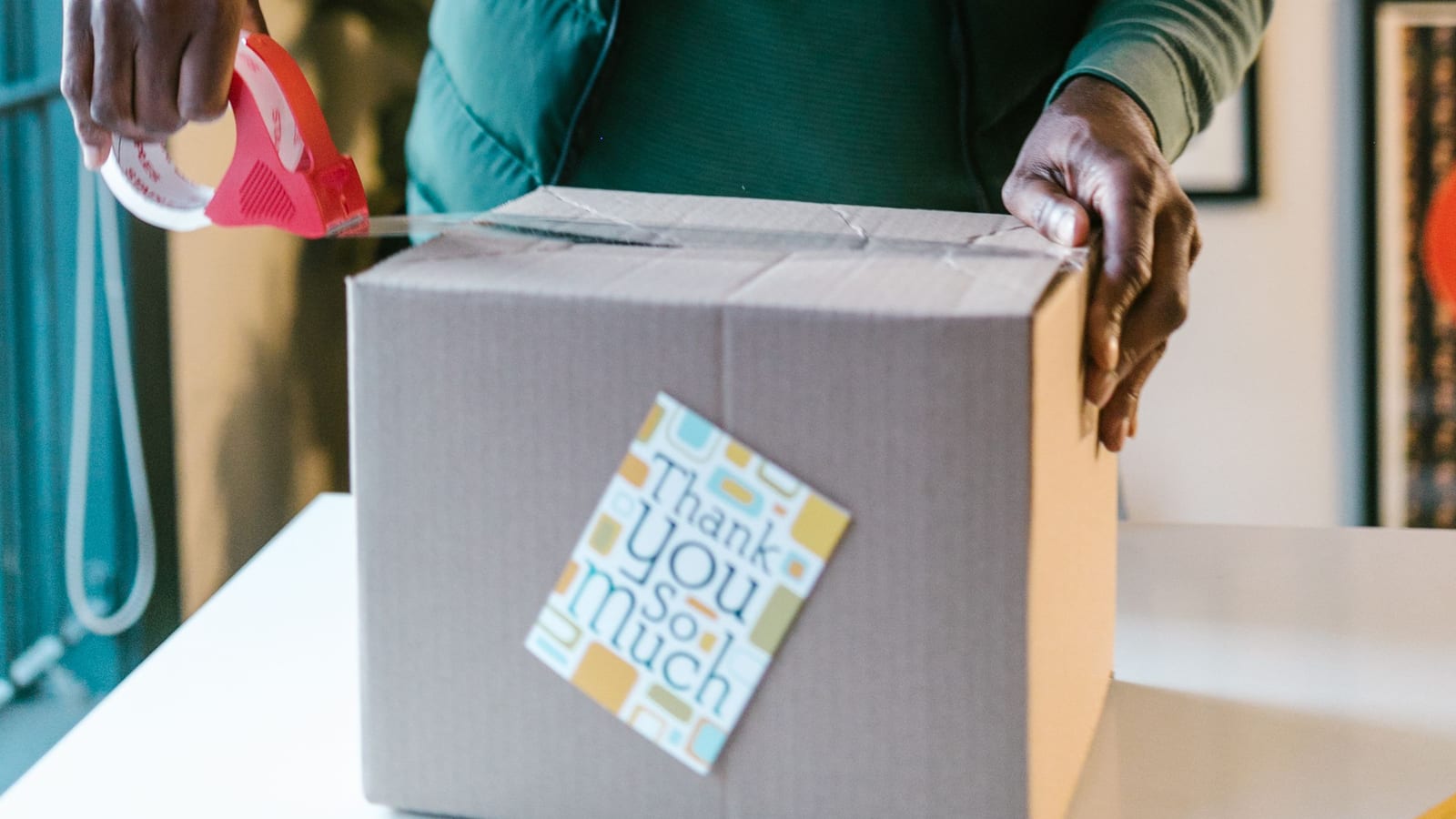 A man packing an order with a thank you card on the box