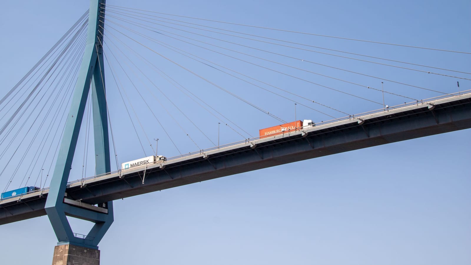 Trucks crossing a large bridge under a clear sky
